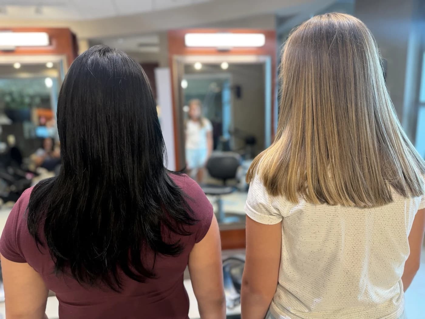 Rear view of two different clients with two real finished hairstyles